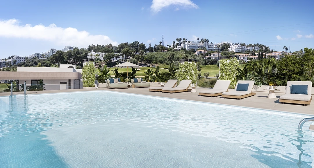 La gran piscina comunitaria, rodeada de tumbonas y exuberante vegetación.