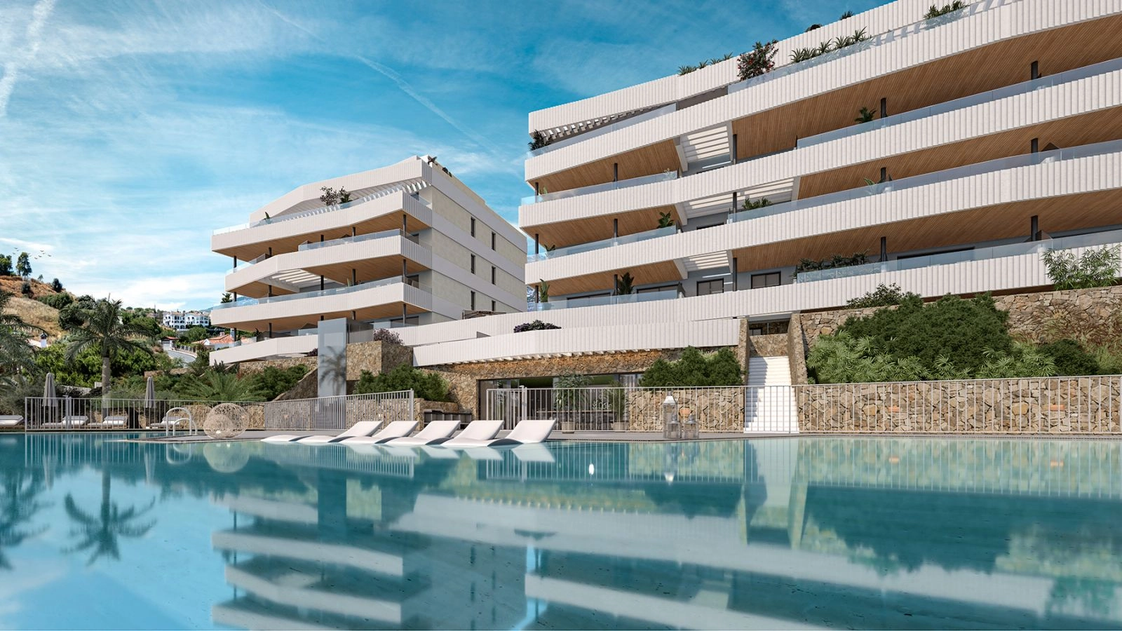 La atractiva piscina comunitaria y la zona para tomar el sol, rodeadas de arquitectura moderna y exuberante vegetación.