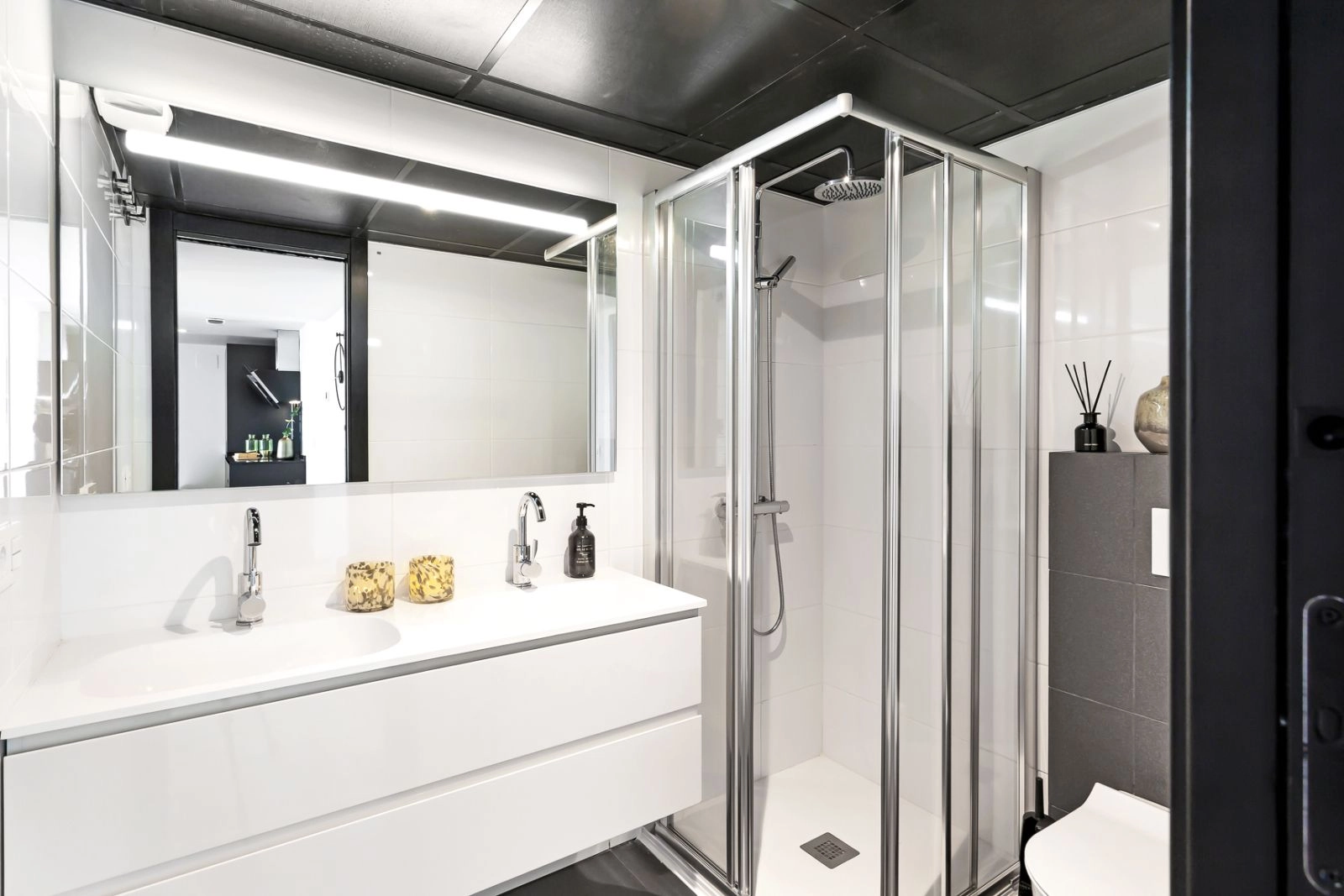 Un cuarto de baño elegante y funcional con accesorios modernos, una ducha a ras de suelo y acabados de alta calidad.