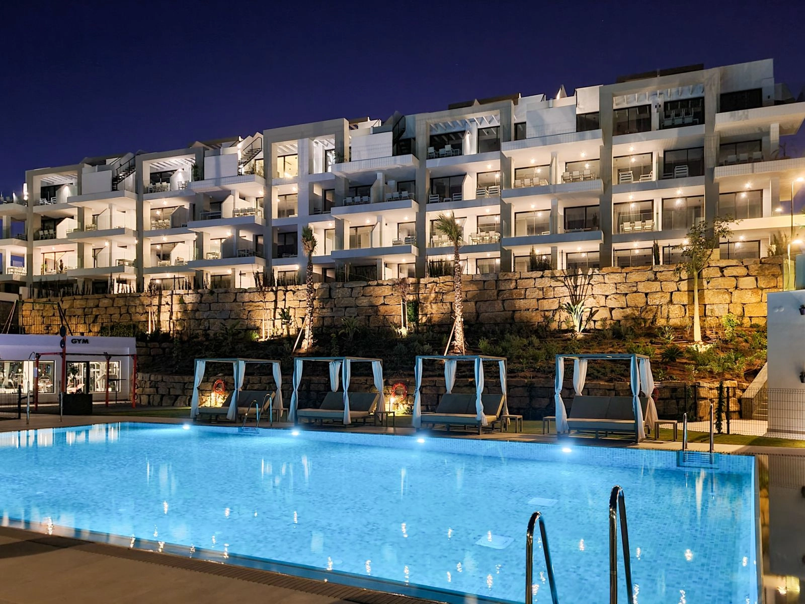 El complejo de apartamentos está bellamente iluminado por la noche, creando un ambiente elegante y seguro.