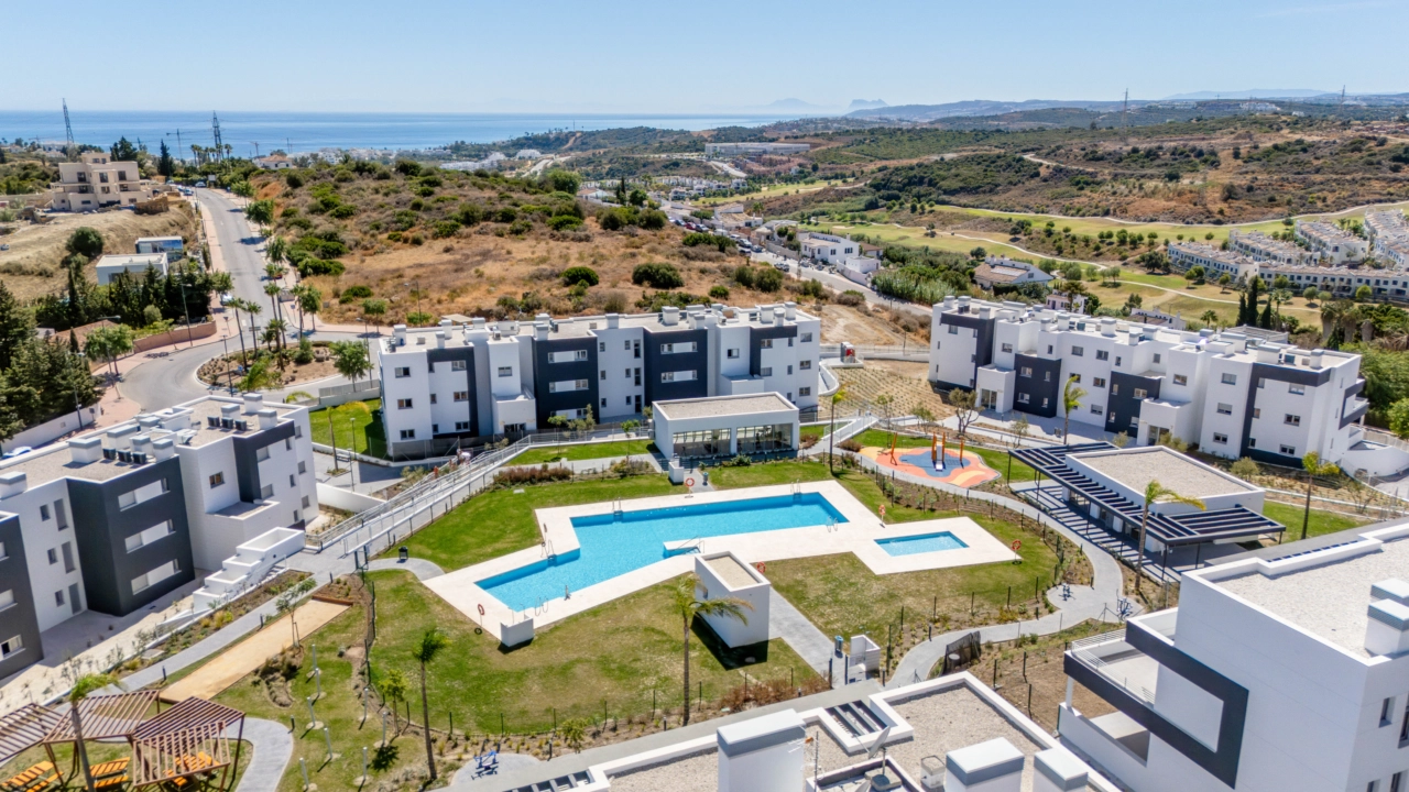 Una maravillosa perspectiva de la urbanización terminada, mostrando las piscinas y las zonas verdes con el mar en el horizonte.