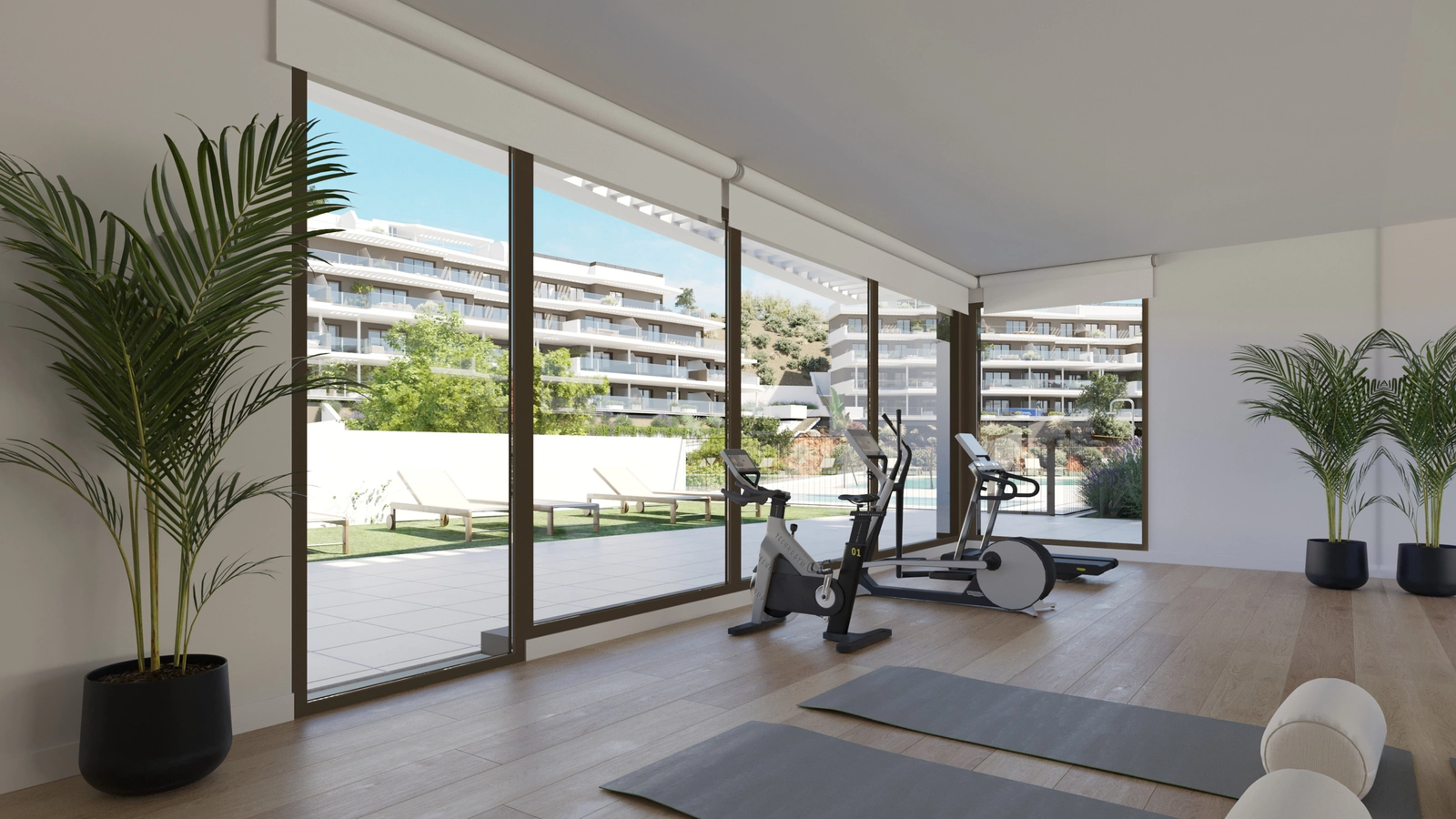 El gimnasio totalmente equipado para residentes, con grandes ventanales con vistas a los jardines y la zona de piscina.