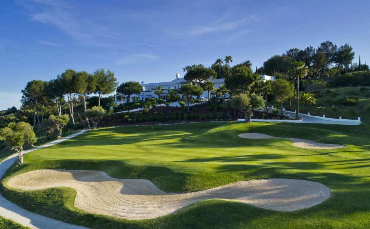 La prestigiosa casa club de Estepona Golf, a pocos pasos de su apartamento, con un telón de fondo de greens impecables.