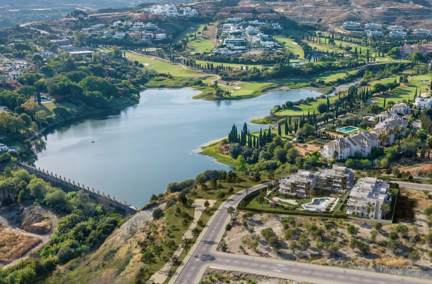 Vista aérea del idílico entorno de la promoción, junto a un lago tranquilo y un campo de golf impecable.