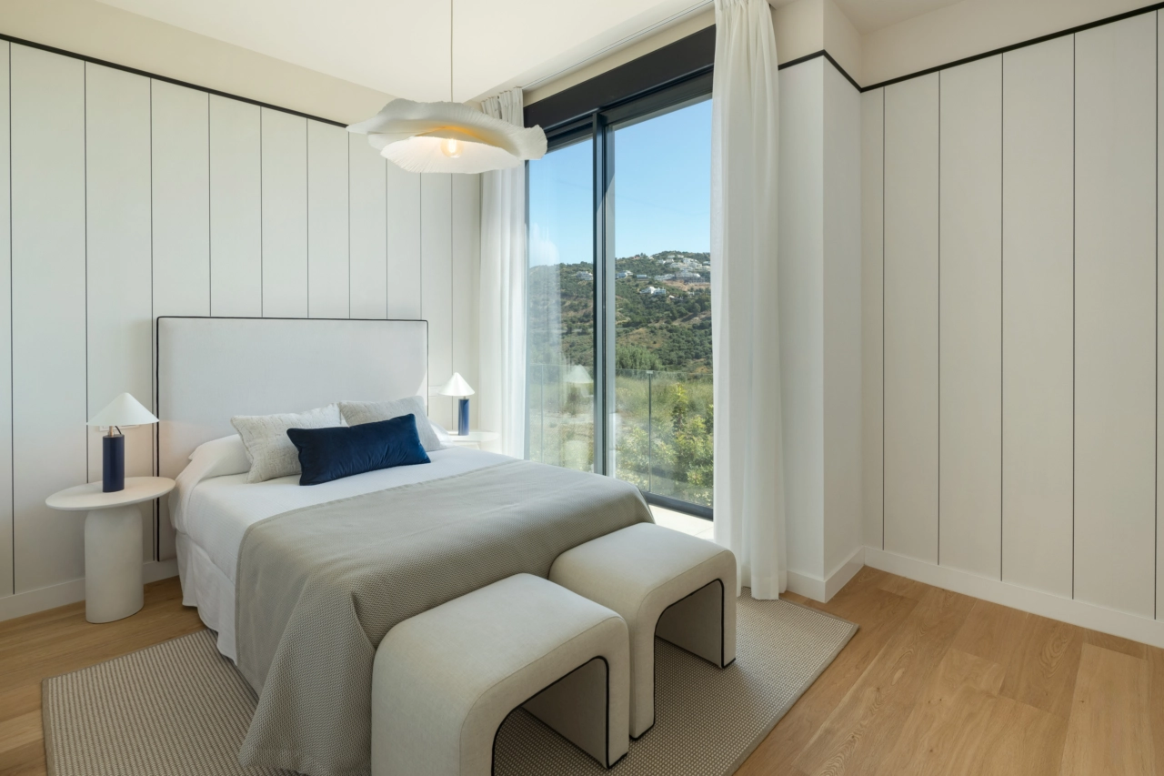 Un cómodo dormitorio de invitados que ofrece serenas vistas del paisaje verde circundante.